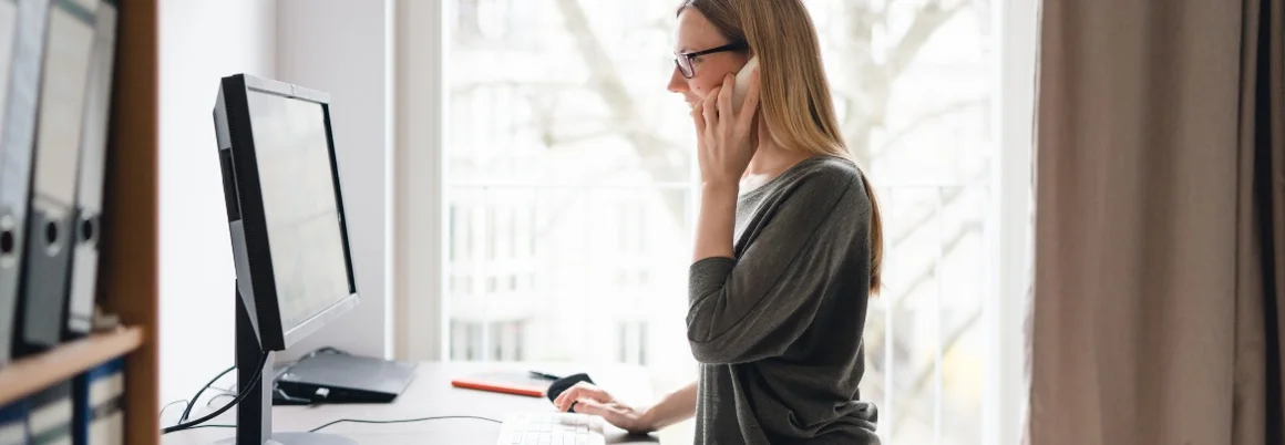 Person telefoniert am Computer.